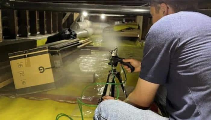Researcher sprays sealant into attic